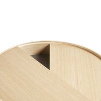 Light oak round table with a smooth natural wood grain and minimalist design, featuring a contrasting dark triangular section.