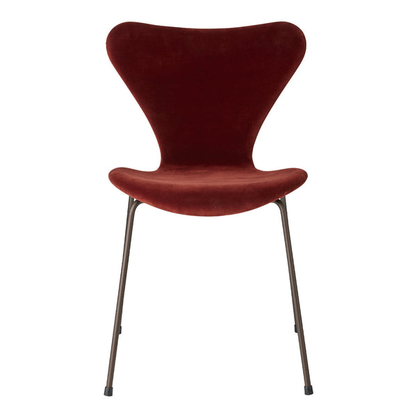 Curved velvet chair in rich burgundy with sleek metal legs, perfect for modern decor.