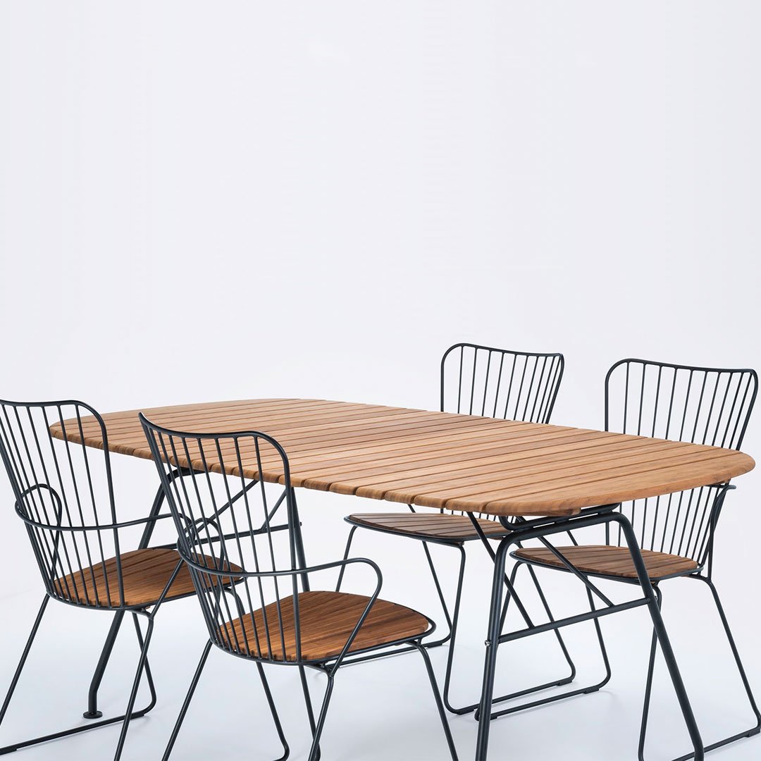 "Wooden tabletop with natural finish paired with black wire chairs in a minimalistic design."