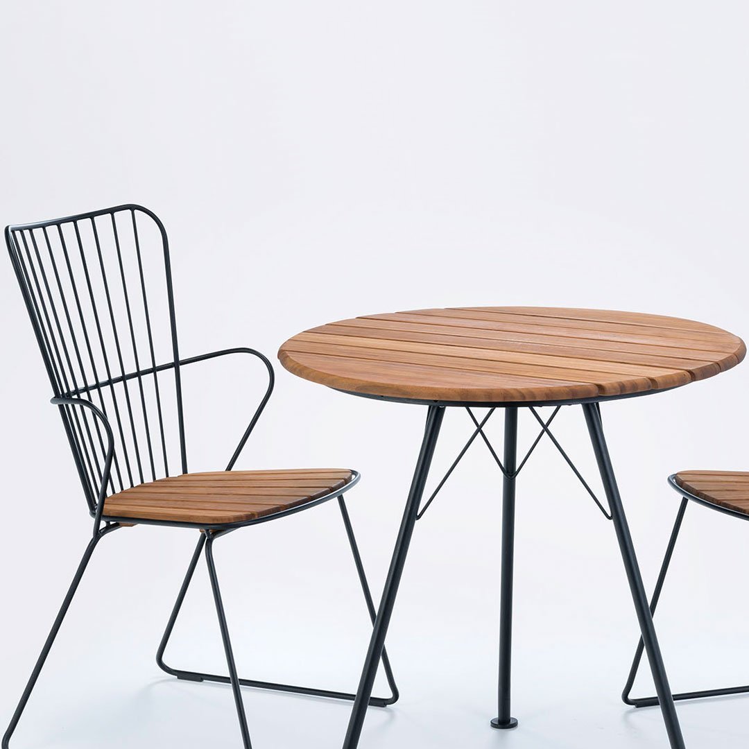 Round wooden table with slatted top, paired with wire chairs featuring a black finish and wooden seat.