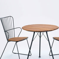 Round wooden table with slatted top, paired with wire chairs featuring a black finish and wooden seat.