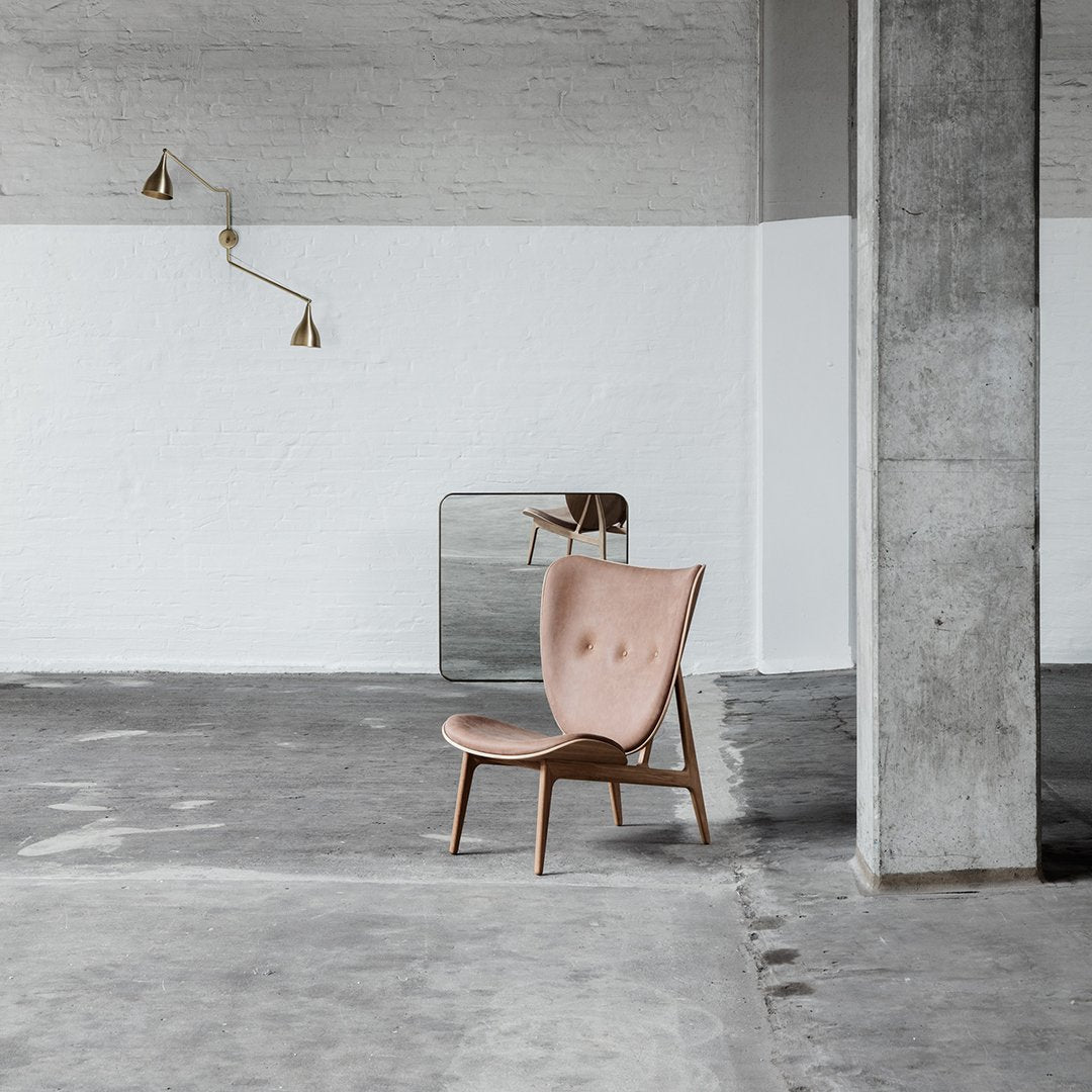 Blush pink upholstered chair with a tufted pattern on a minimalist gray concrete floor and white wall backdrop.