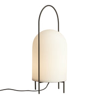 Modern white ribbed lamp with a black metal frame and arching handle, perfect for stylish decor.
