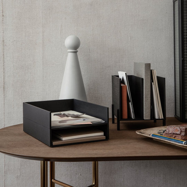 Black storage boxes atop a wooden table with a white decorative piece and minimalist magazine holders.