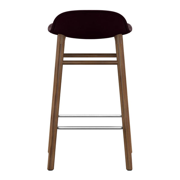 Dark burgundy velvet bar stool with wooden legs and silver footrest, featuring a sleek, minimalist design.
