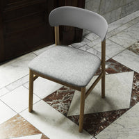 Gray upholstered chair with a curved white backrest on a patterned marble floor. Elegant and modern design.
