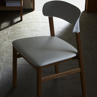 Modern chair featuring a sleek white seat and a natural wood frame, perfect for contemporary decor.