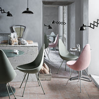 Modern dining chairs in soft green and pink hues, with a minimalist, sleek design against a neutral gray backdrop.