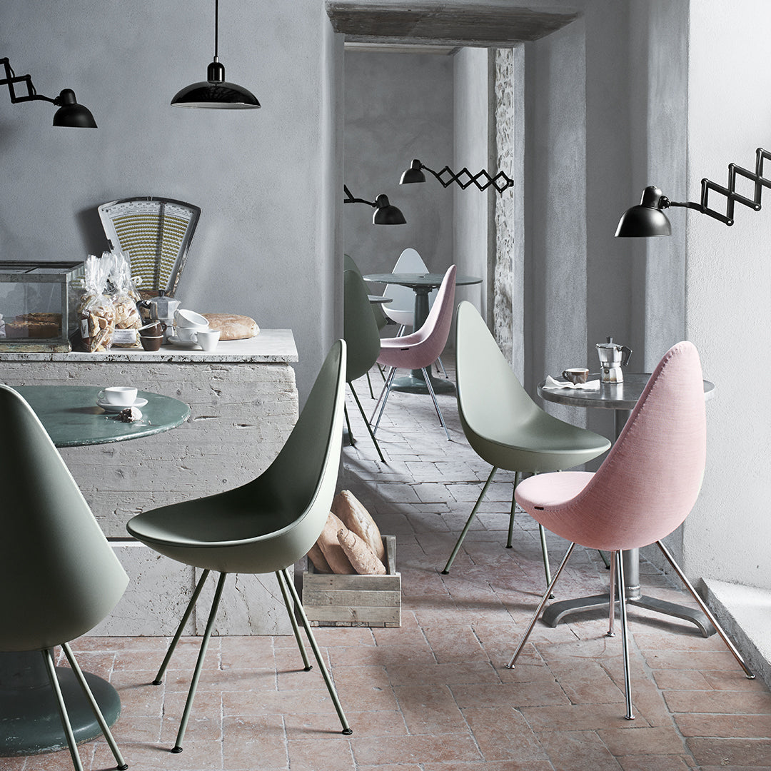 Modern dining chairs in soft green and pink hues, with a minimalist, sleek design against a neutral gray backdrop.