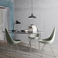 Modern dining setup featuring gray table, mint green chairs, and black pendant light against textured blue wall.