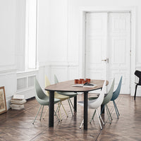 Modern wooden dining table with pastel-colored chairs in soft shades of green, blue, and yellow against a minimalist backdrop.