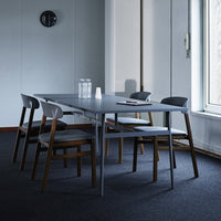 Contemporary gray dining table with black and wood-accented chairs in a minimalist setting. Stylish and modern design.