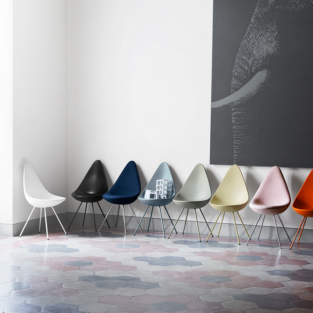 "Colorful modern chairs in hues of white, black, blue, beige, and pink against a patterned floor."
