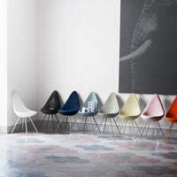 "Colorful modern chairs in hues of white, black, blue, beige, and pink against a patterned floor."