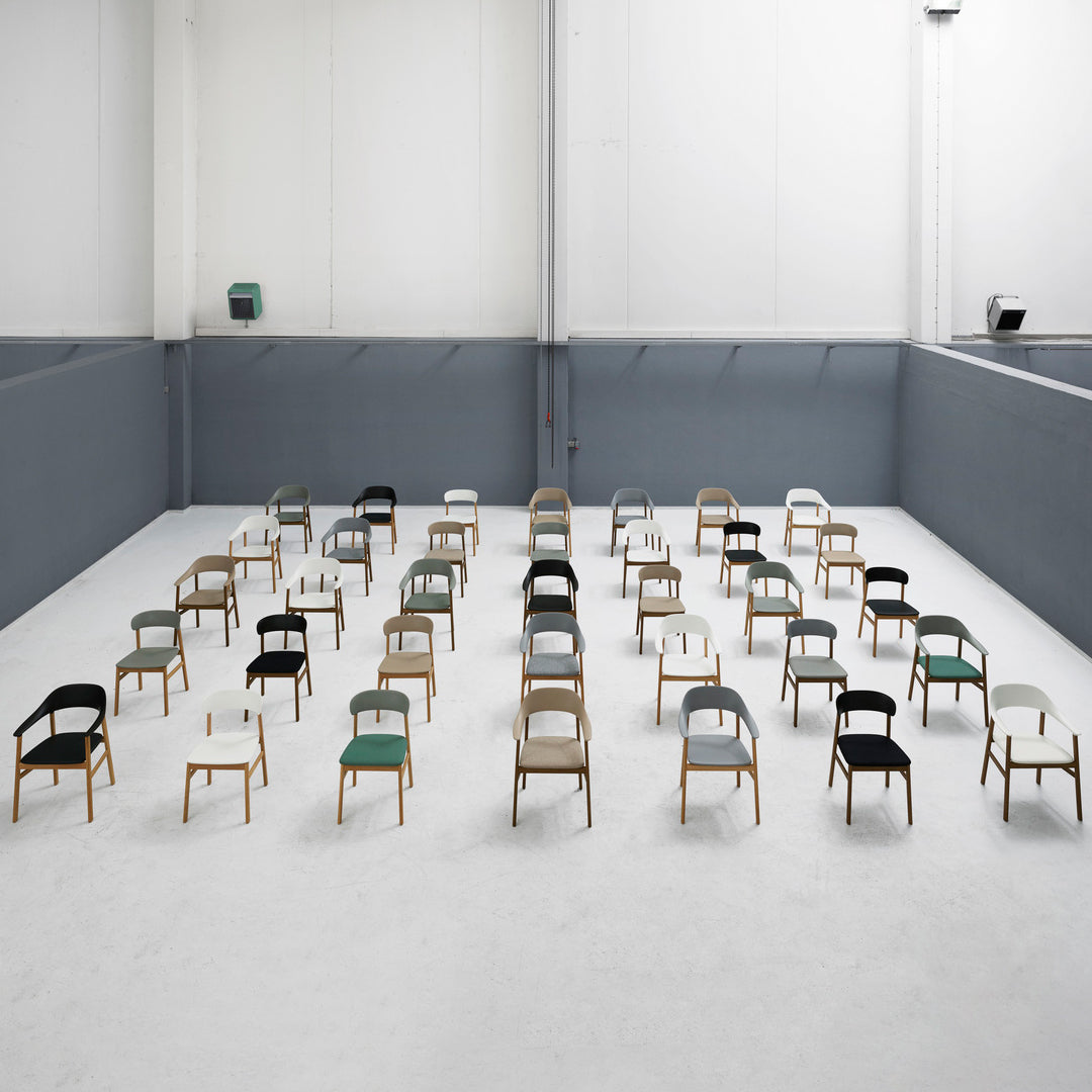 Colorful chairs in distinct patterns: green, black, gray, and white, arranged in a modern, minimalist setting.