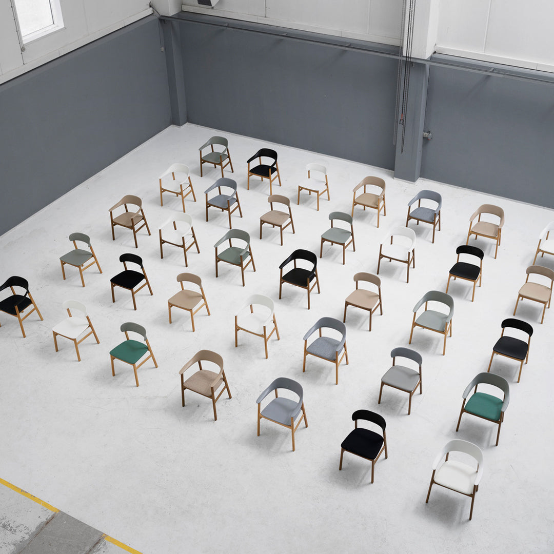 Colorful chairs with various patterns, including gray, green, white, black, and natural wood, arranged in a spacious setting.