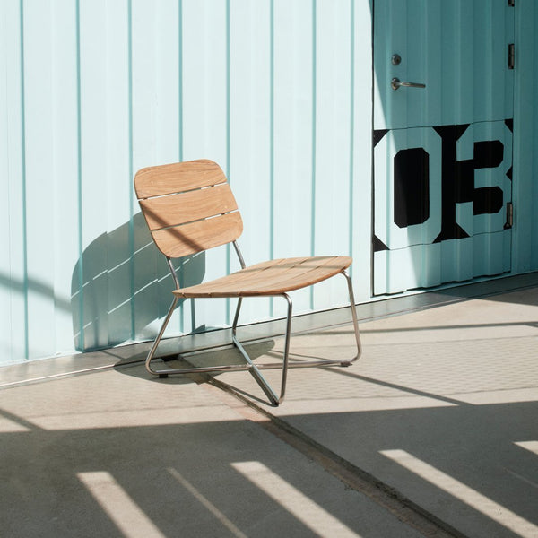 Modern wooden chair with a minimalist design, featuring a natural wood finish against a light blue background.