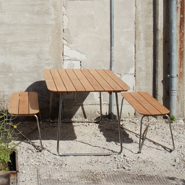 Brown slatted tabletop with matching benches, set against a neutral concrete background. Modern minimalist outdoor furniture.