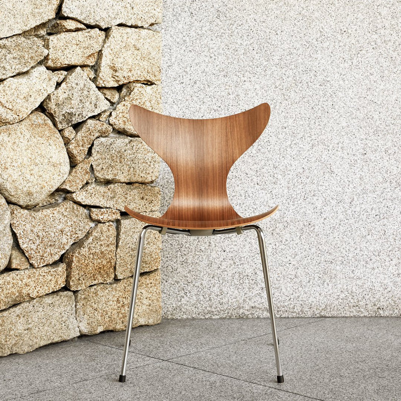 Elegant wooden chair with a warm brown finish, featuring a smooth, curved design against a textured stone backdrop.