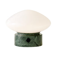 White glass lamp with a smooth, oval shape resting on a green marble base with intricate patterns.