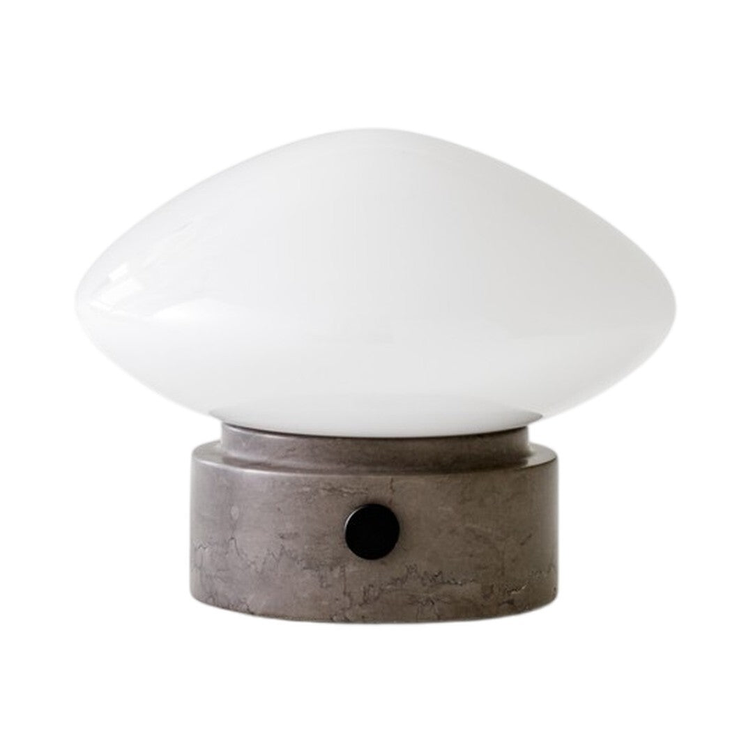 White glass lamp shade with a smooth, curved design atop a textured gray base and a simple black switch.
