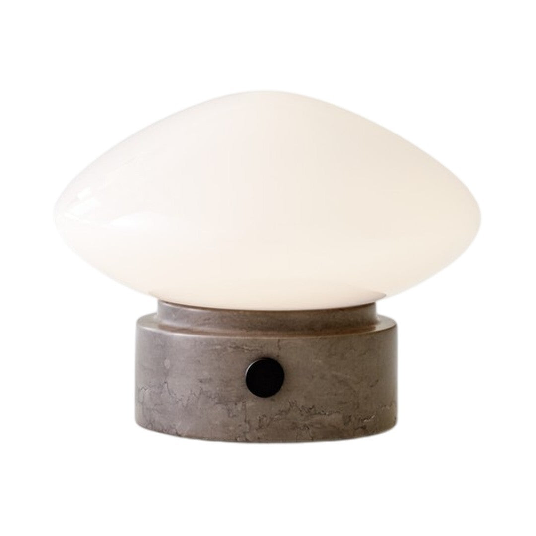 White glass lampshade with smooth curves, set on a textured gray concrete base, accented by a black knob.
