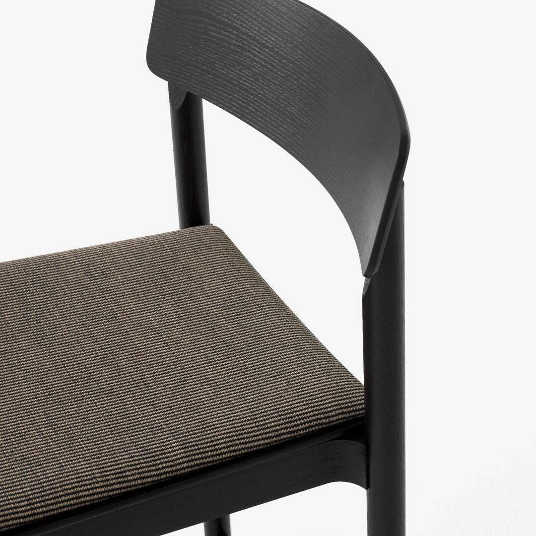 Black chair with a textured brown seat. Simple, modern design featuring smooth surfaces and subtle patterns.
