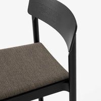 Black chair with a textured brown seat. Simple, modern design featuring smooth surfaces and subtle patterns.