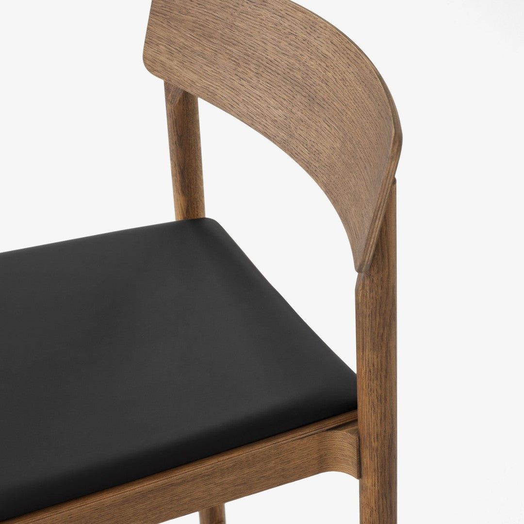 "Wooden chair with a natural finish and a sleek black cushion, featuring smooth lines and a modern aesthetic."