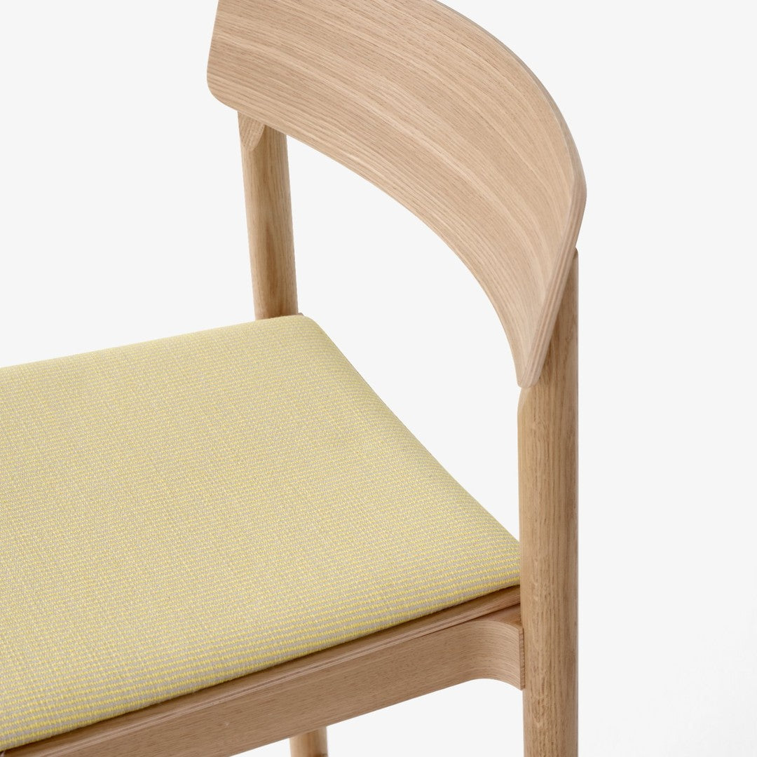 "Light wood chair with a soft yellow patterned seat, combining natural tones and contemporary design."