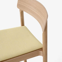 "Light wood chair with a soft yellow patterned seat, combining natural tones and contemporary design."