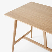 Natural oak wood table with a smooth, light brown finish and minimalist design featuring tapered legs.