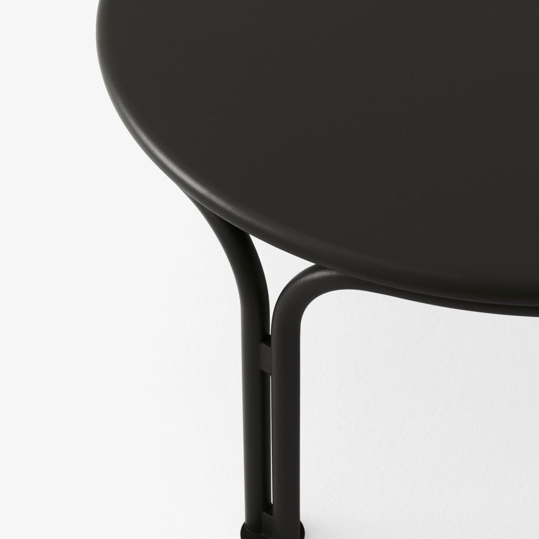 Round black table with sleek matte finish and minimalist black metal legs. Stylish and contemporary design.