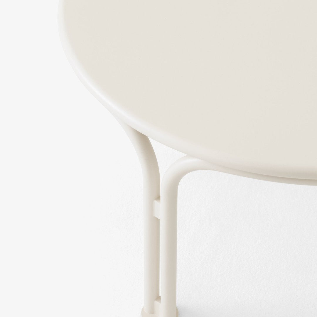 "Round table with a smooth, creamy beige surface and light-colored legs, against a minimalistic white background."