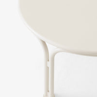 "Round table with a smooth, creamy beige surface and light-colored legs, against a minimalistic white background."