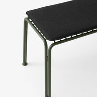 Black cushion on olive green metal bench with minimalistic design and clean lines. Perfect for modern décor.