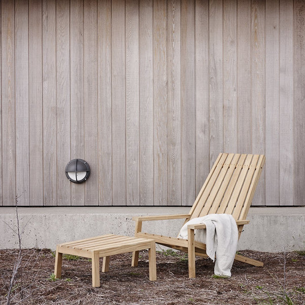 Natural wooden lounge chair and side table with a light grain pattern against a simple, neutral backdrop.