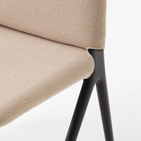 Beige textured upholstery on a modern chair with sleek black metal legs. Elegant and minimal design.