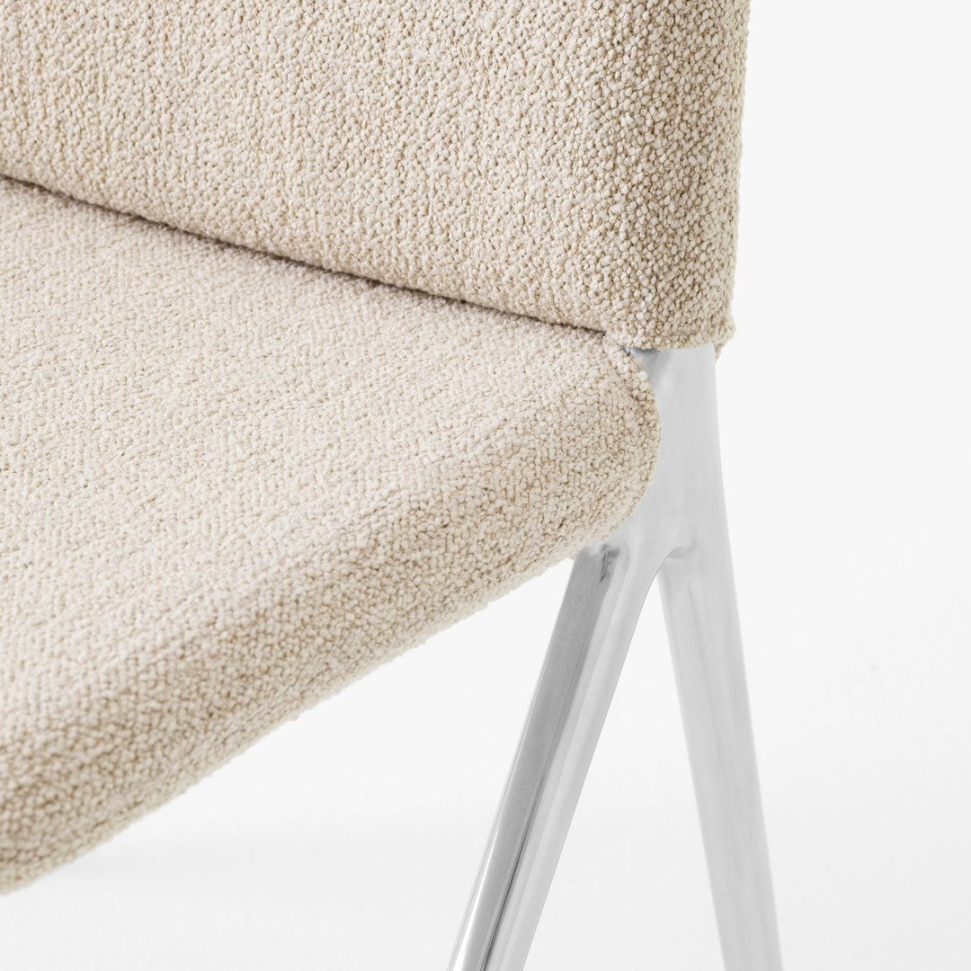 Beige textured upholstery with a subtle pattern on a chair, featuring sleek silver metal legs.
