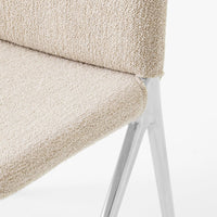 Beige textured upholstery with a subtle pattern on a chair, featuring sleek silver metal legs.