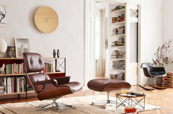 Modern brown leather lounge chair and ottoman, accented by neutral tones and geometric patterns in a minimalist setting.