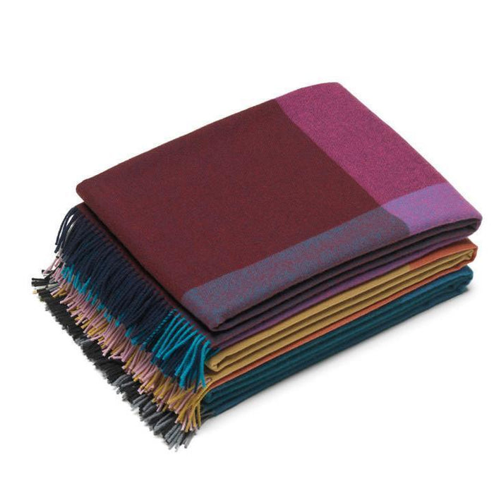 "Stacked scarves featuring rich burgundy, purple, teal, mustard, and striped patterns with fringed edges."