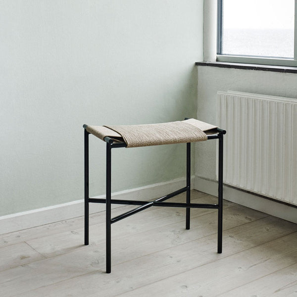 Black metal stool with a beige woven seat, minimalist design, perfect for modern interiors.