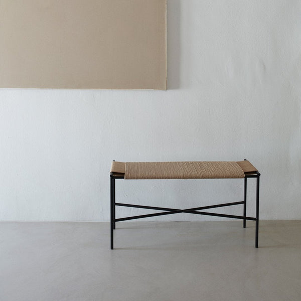 Natural woven pattern with a beige seat and black metal frame; minimalist design against a neutral backdrop.