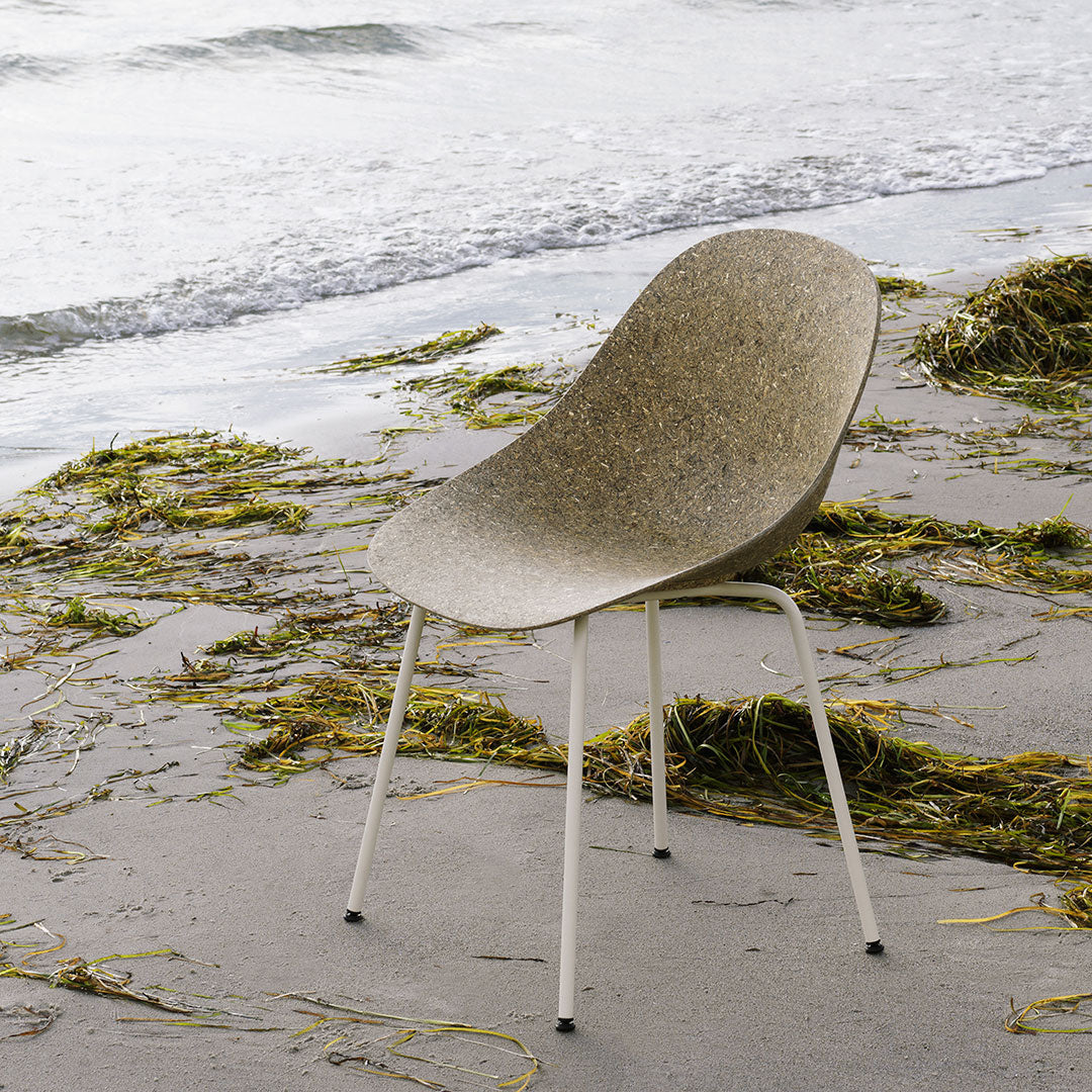 Light brown textured chair against a natural beach backdrop with subtle green seaweed patterns.