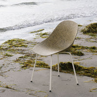 Light brown textured chair against a natural beach backdrop with subtle green seaweed patterns.