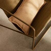 Brown and olive green chair with a textured tan pillow, featuring a sleek metal frame and minimalistic design.