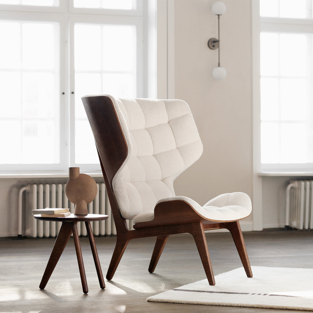 "Contemporary beige chair with tufted pattern and stylish wooden legs in a bright, minimalist interior."