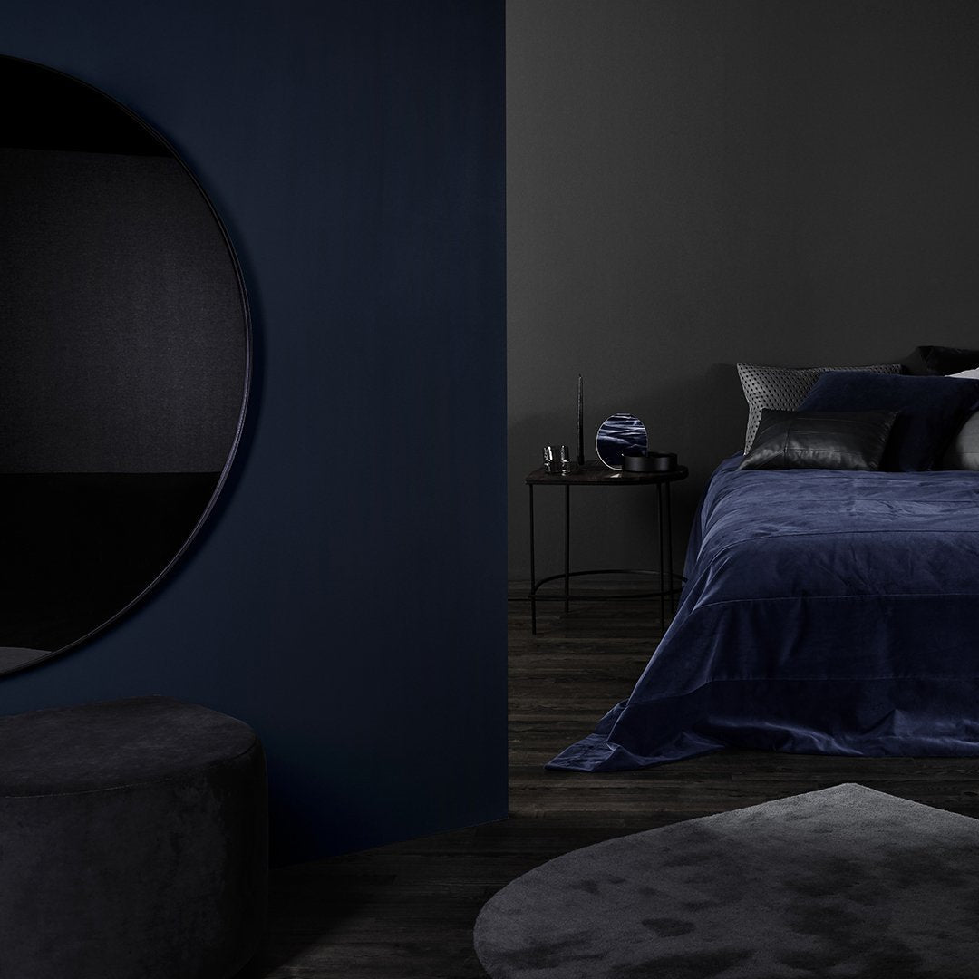 Navy blue bedding set on a dark gray backdrop, featuring smooth textures and elegant, muted tones.