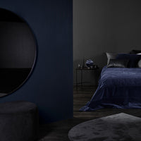 Navy blue bedding set on a dark gray backdrop, featuring smooth textures and elegant, muted tones.